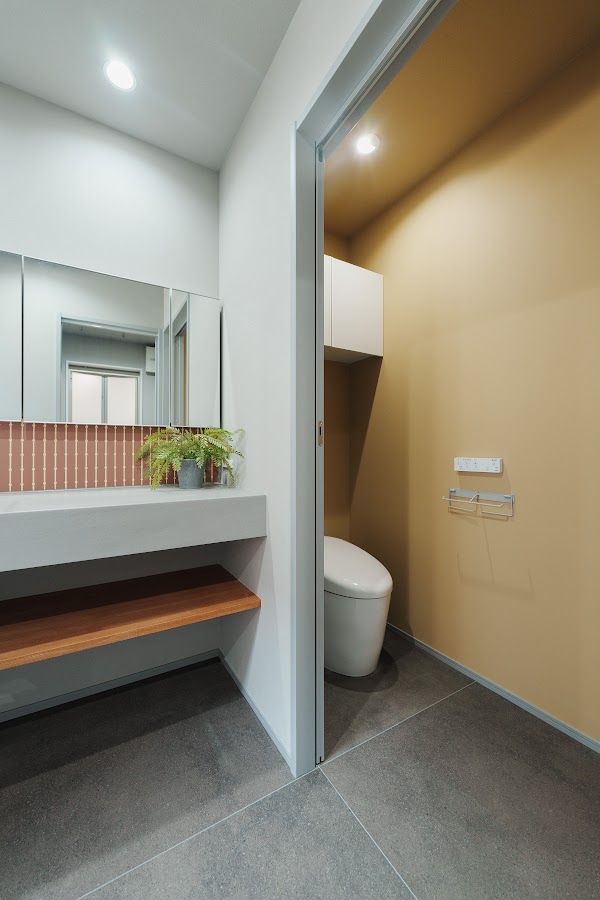 埋込ミラーと黄色の壁紙のトイレ空間