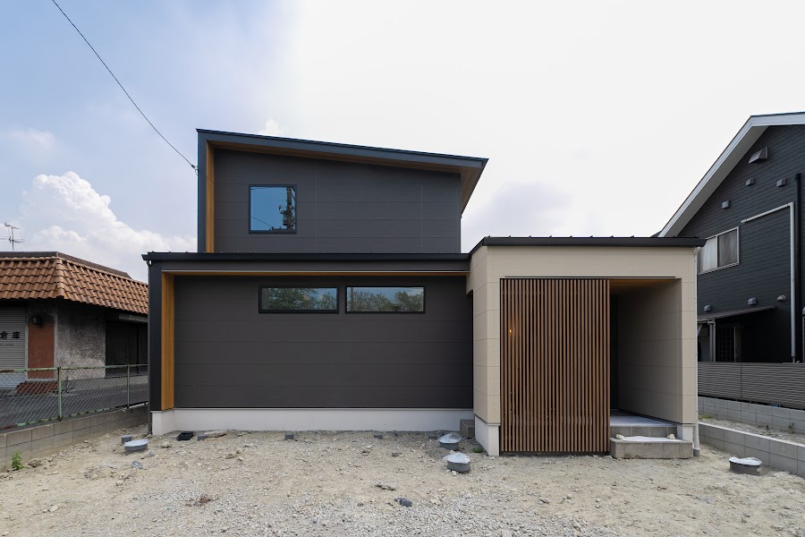 木目格子と黒い外壁が並ぶ建物の外観とアプローチ